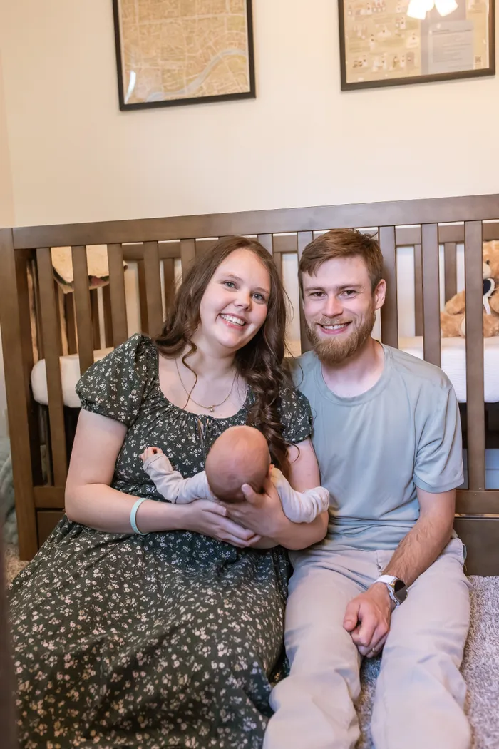 Caeden and Julia sitting together with their infant son